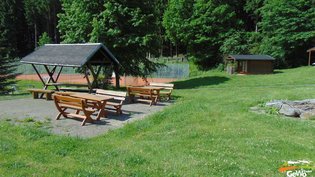 Grillplatz mit Feuerstelle und Tennisplatz im Hintergrund